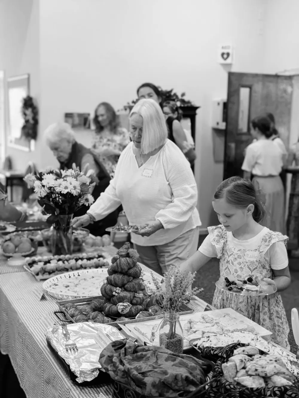A young girl and older church members at a fellowship meal