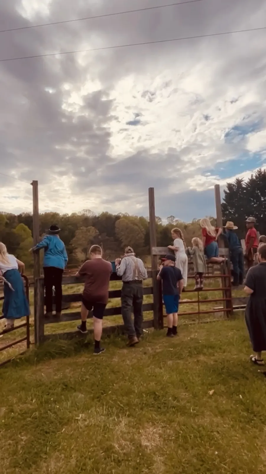 Church families gathered along a farm fence on a spring afternoon