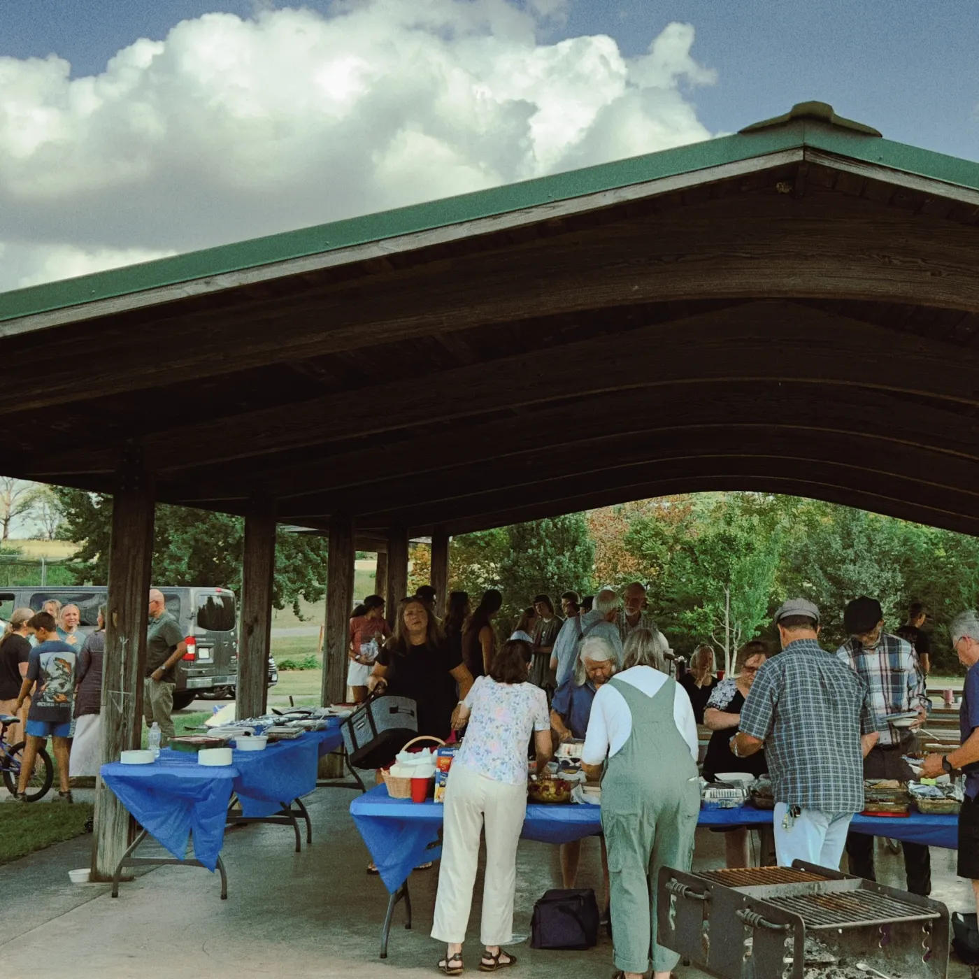 Church families sharing a fellowship meal under a picnic pavilion
